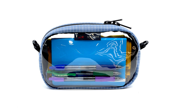 A Acuity (faded blue) with white grid pattern (Halcyon) 3D Clear Organizer Cube filled with sundries.
